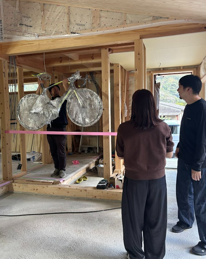 HT様邸の現場で自転車を掲げて展示位置を確認する様子